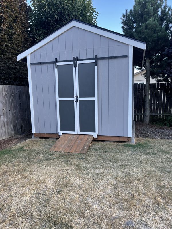 Finished backyard shed with twin barn doors and white trim